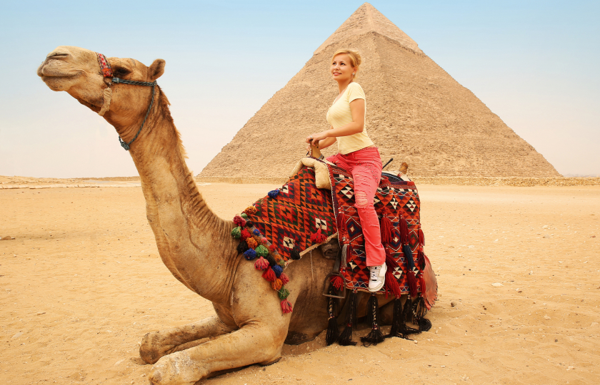 Tourist woman on camel in Giza. Young blonde near Pyramid of Khafre, Egypt